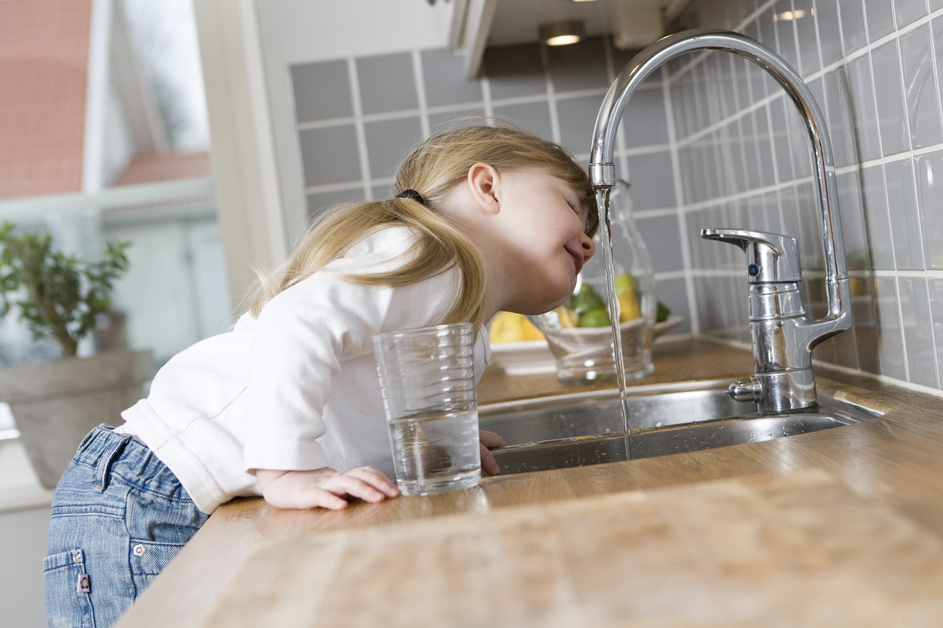 小女孩在厨房里喝水龙头里的水