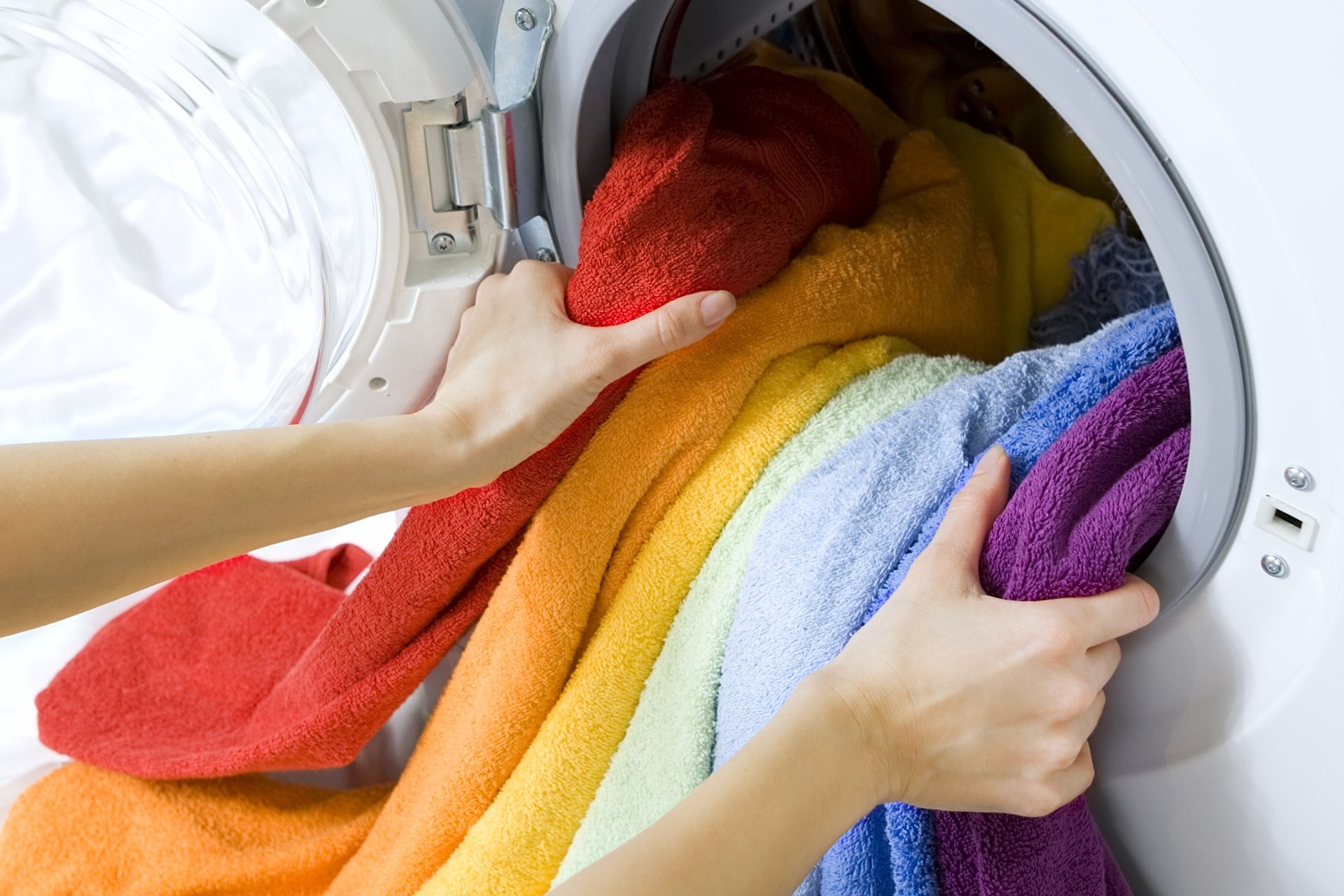 采取颜色衣裳的妇女从洗衣机