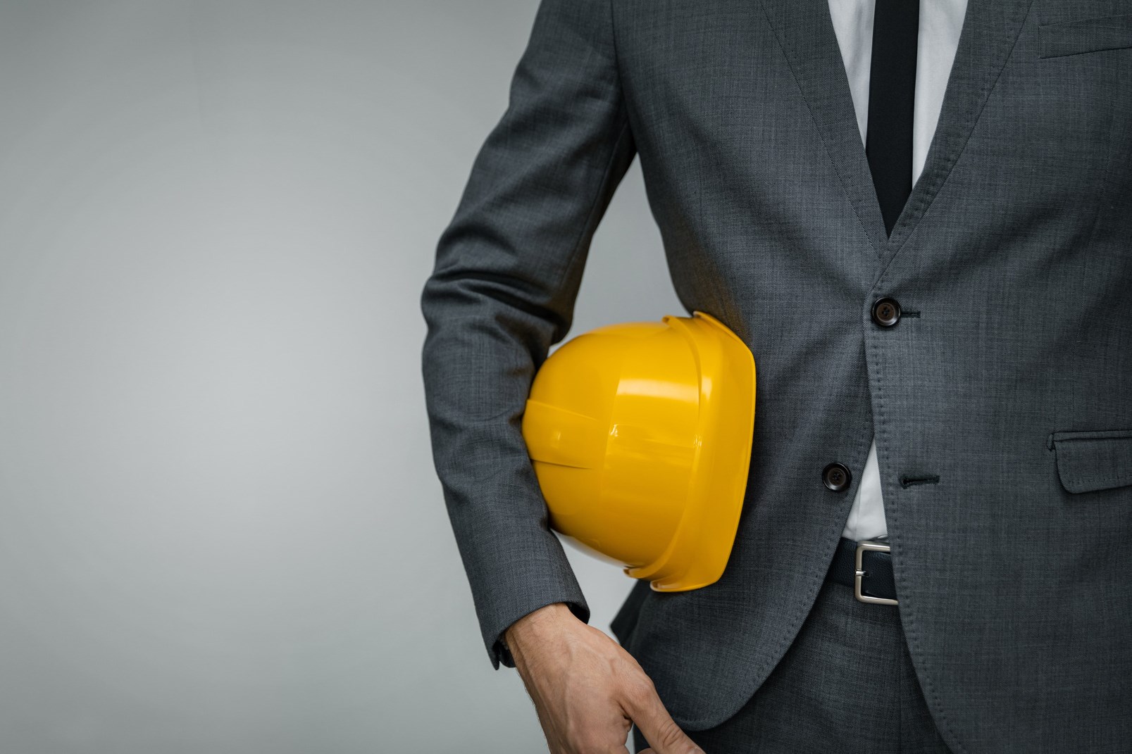 建筑业企业-商人持有黄色安全帽下的灰色背景与复制空间
